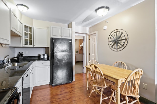 kitchen featuring black refrigerator, sink, dishwasher, and white cabinets