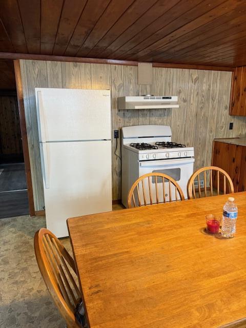 unfurnished dining area featuring wood ceiling and wooden walls