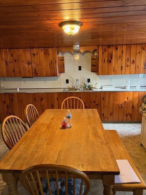 kitchen with tasteful backsplash, wood ceiling, wooden walls, and sink