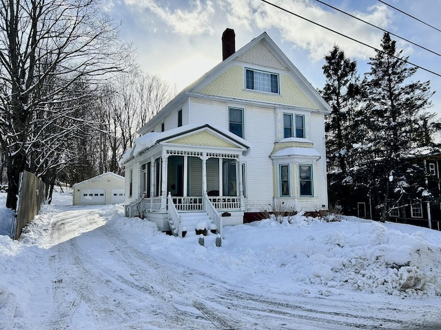 victorian home featuring covered porch, a garage, and an outdoor structure