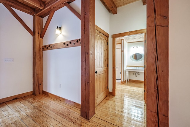 corridor with vaulted ceiling with beams, light hardwood / wood-style flooring, and wooden ceiling