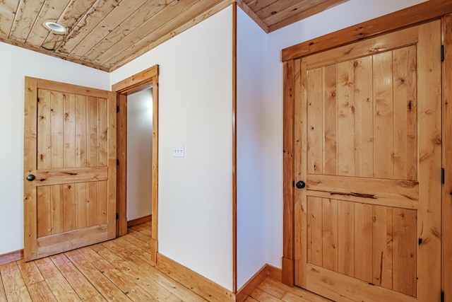 hallway with light wood-type flooring and wood ceiling