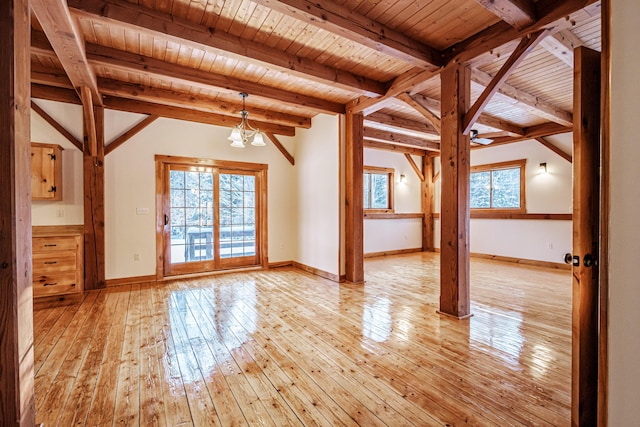 unfurnished living room featuring beam ceiling, light hardwood / wood-style flooring, a healthy amount of sunlight, and wood ceiling