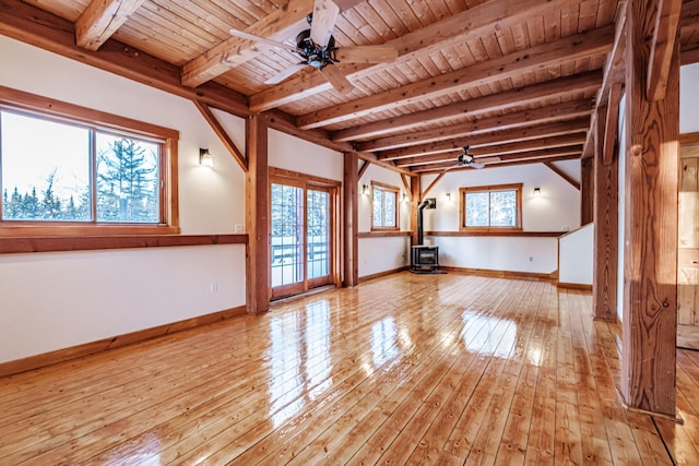 unfurnished living room featuring a wood stove, beamed ceiling, wooden ceiling, and light hardwood / wood-style floors