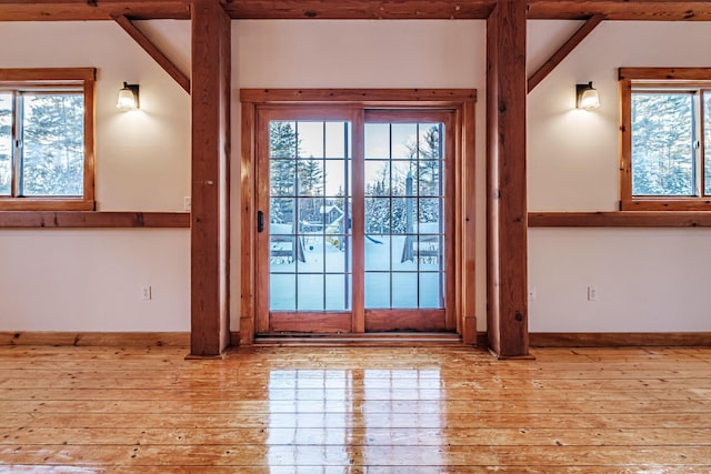 doorway featuring light wood-type flooring, vaulted ceiling, and a healthy amount of sunlight