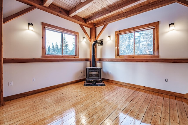 unfurnished living room featuring light hardwood / wood-style floors, a wood stove, beam ceiling, and wooden ceiling