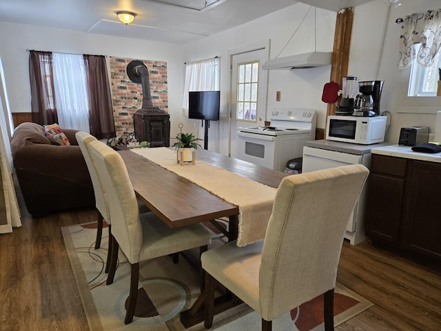 dining space with a wood stove, plenty of natural light, and dark wood-type flooring