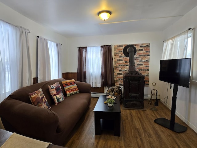 living room featuring plenty of natural light, dark hardwood / wood-style flooring, a wood stove, and baseboard heating