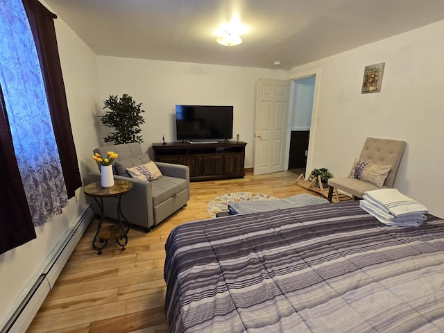 bedroom with light hardwood / wood-style floors and a baseboard heating unit