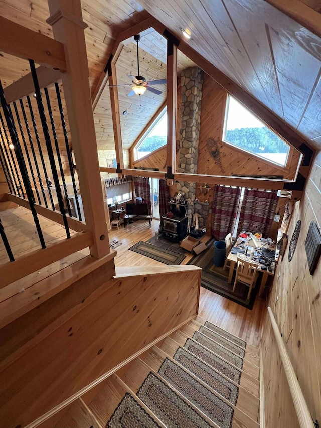 staircase featuring a wood stove, ceiling fan, a skylight, wooden ceiling, and hardwood / wood-style floors