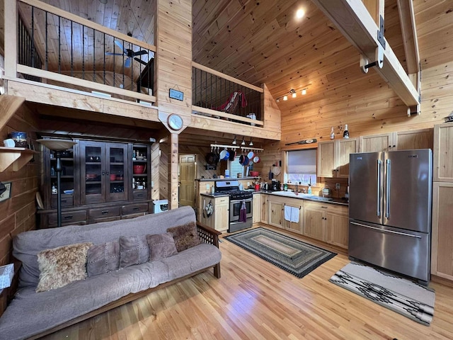 kitchen featuring wood walls, high vaulted ceiling, stainless steel appliances, and light hardwood / wood-style floors