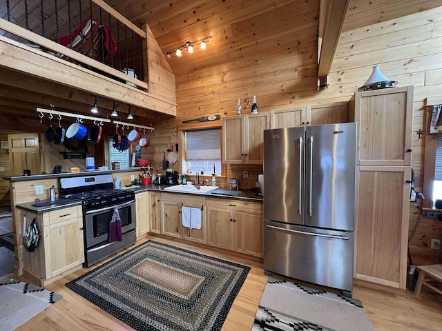 kitchen featuring wood walls, sink, appliances with stainless steel finishes, light hardwood / wood-style floors, and kitchen peninsula