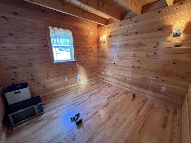 interior space with wood walls, beam ceiling, and light wood-type flooring