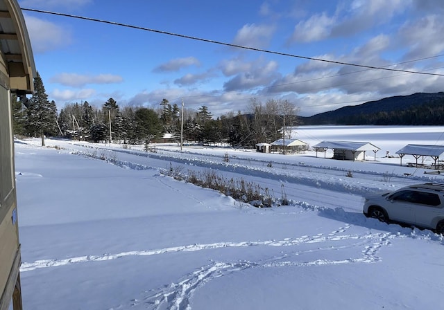 yard covered in snow featuring a mountain view