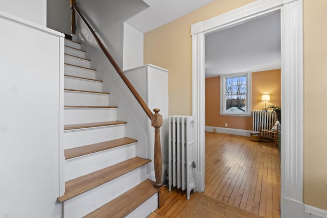 stairs featuring hardwood / wood-style floors and radiator heating unit