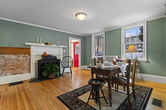 dining room featuring radiator, hardwood / wood-style floors, and ornamental molding