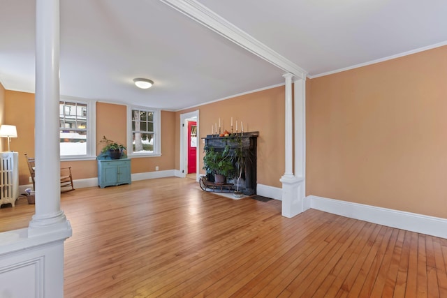 unfurnished living room featuring decorative columns, light hardwood / wood-style flooring, and crown molding