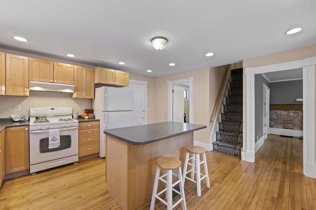 kitchen with a breakfast bar, white appliances, a center island, and light hardwood / wood-style floors