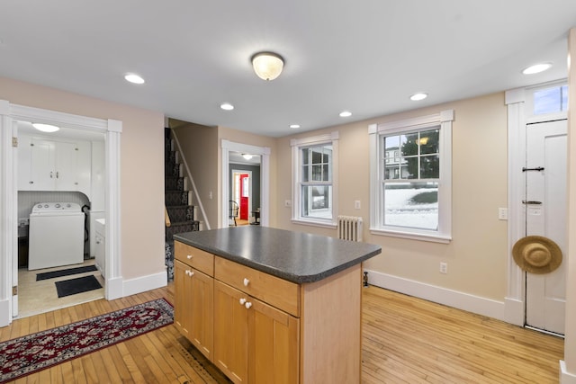 kitchen featuring washer / clothes dryer, radiator heating unit, a kitchen island, and light hardwood / wood-style floors