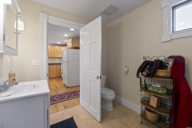 bathroom featuring wood-type flooring, vanity, and toilet