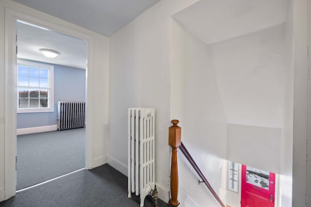 hall featuring radiator and dark carpet