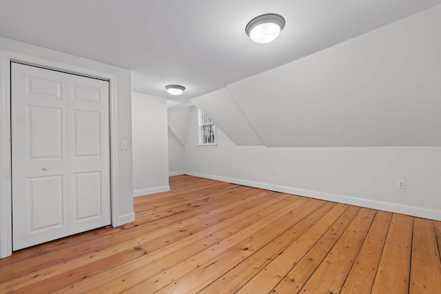 additional living space with light hardwood / wood-style floors and vaulted ceiling