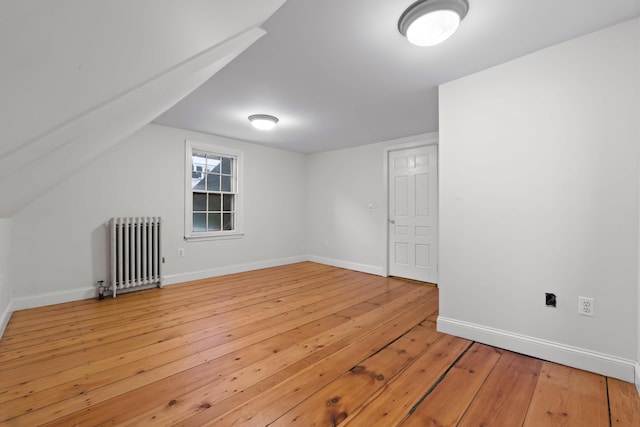 bonus room with hardwood / wood-style flooring, radiator, and vaulted ceiling