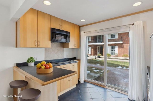 173 Pine St Unit 1P, Portland, ME 04102 - kitchen with a peninsula, dark countertops, dark tile patterned flooring, a breakfast bar, and black appliances