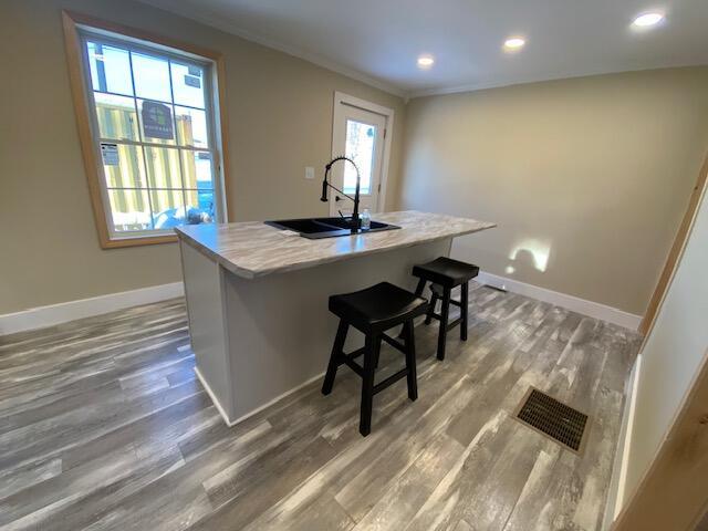 kitchen featuring baseboards, visible vents, light countertops, and wood finished floors