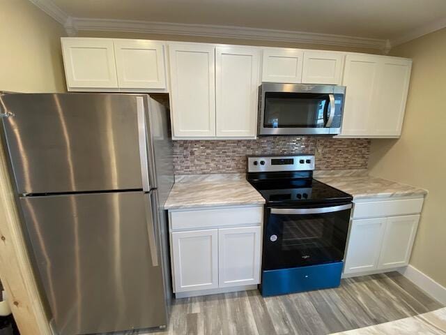 kitchen featuring stainless steel appliances, white cabinets, ornamental molding, and tasteful backsplash