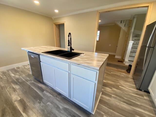 kitchen featuring stainless steel appliances, dark wood finished floors, a sink, and ornamental molding