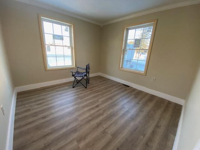 spare room featuring baseboards, ornamental molding, wood finished floors, and a healthy amount of sunlight