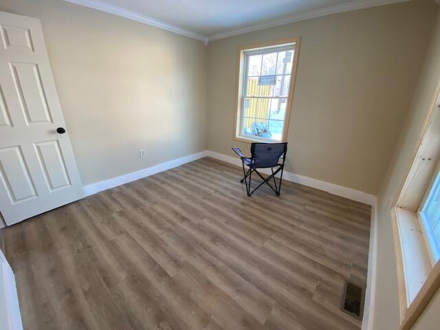 unfurnished bedroom featuring visible vents, crown molding, baseboards, and wood finished floors