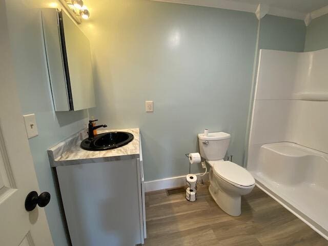 full bath with crown molding, toilet, vanity, wood finished floors, and walk in shower