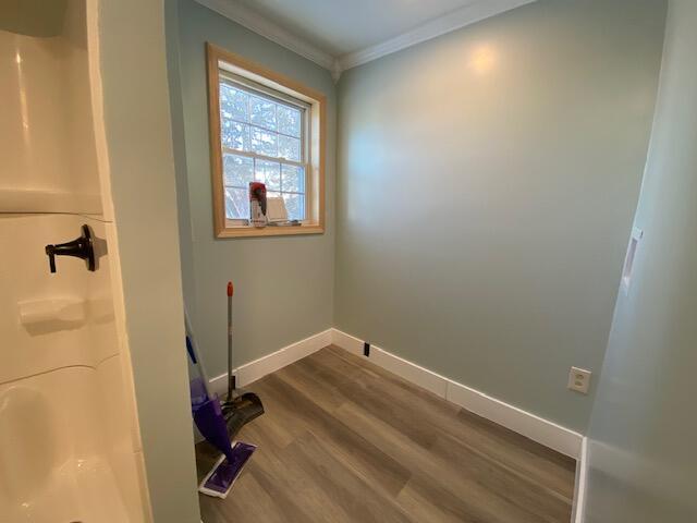 interior space with wood finished floors, crown molding, baseboards, and walk in shower