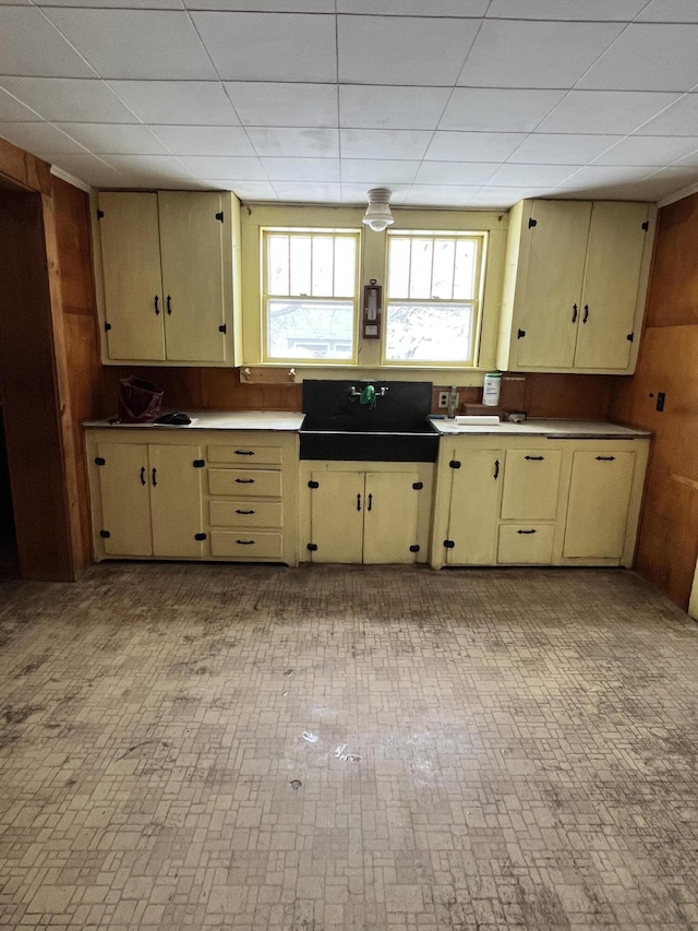 90 Canada Rd, Moscow, ME 04920 - kitchen with cream cabinetry, a paneled ceiling, wooden walls, and brick patterned floors