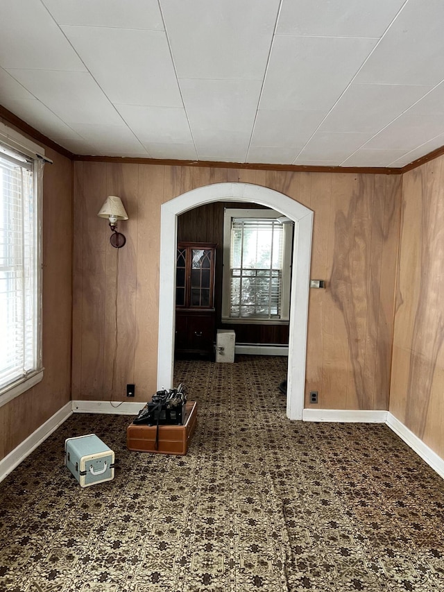 interior space featuring dark carpet, wooden walls, and a baseboard radiator