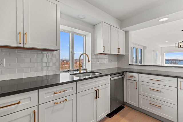 kitchen with dishwasher, sink, tasteful backsplash, light hardwood / wood-style floors, and white cabinets