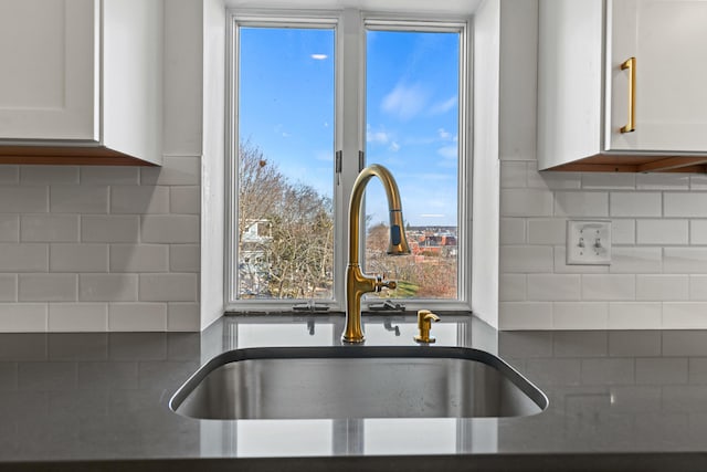 kitchen featuring white cabinets, decorative backsplash, and sink