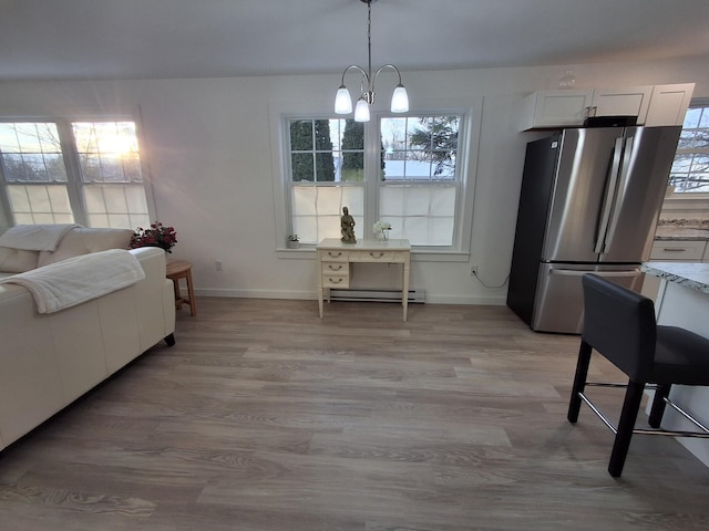 interior space with a notable chandelier, light hardwood / wood-style floors, plenty of natural light, and a baseboard radiator