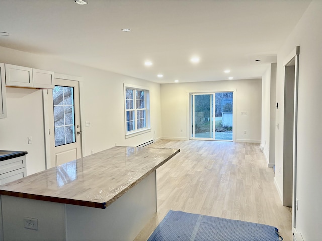 kitchen with a center island, a baseboard radiator, butcher block countertops, light hardwood / wood-style floors, and white cabinetry