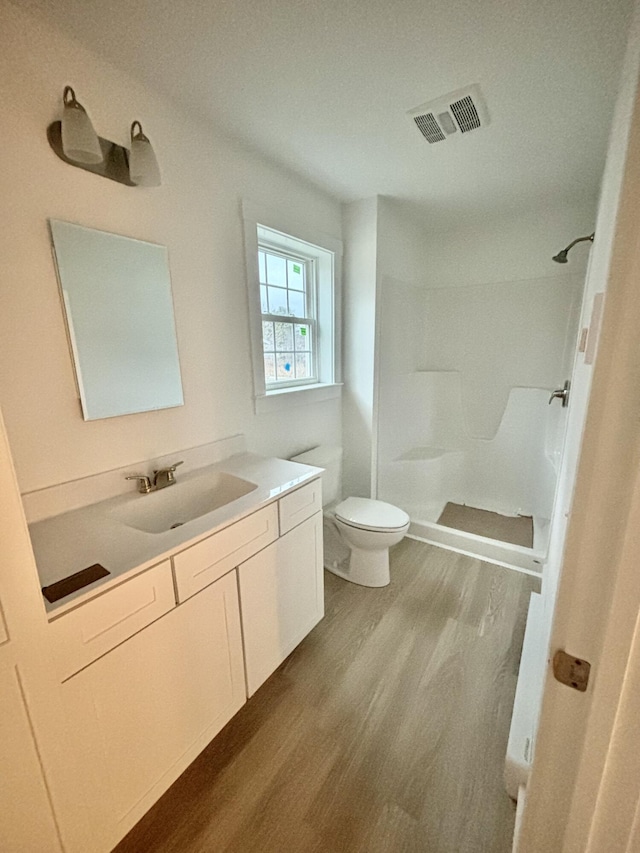 bathroom featuring hardwood / wood-style floors, vanity, toilet, and walk in shower