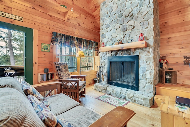 living room featuring hardwood / wood-style flooring, plenty of natural light, wood walls, and a stone fireplace