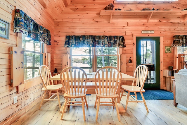 dining space featuring wooden walls, light hardwood / wood-style floors, and lofted ceiling