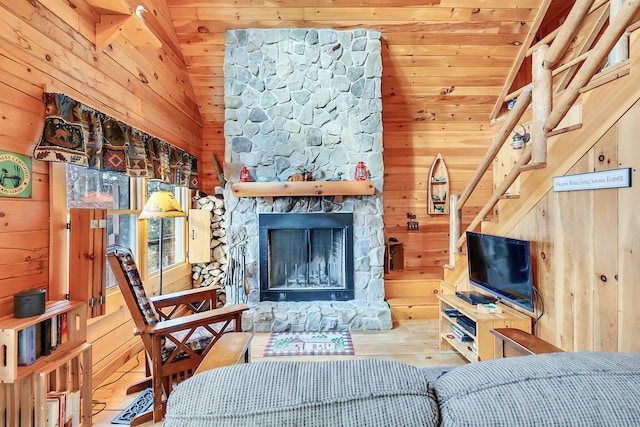 living room with hardwood / wood-style flooring, a stone fireplace, wooden walls, and wood ceiling