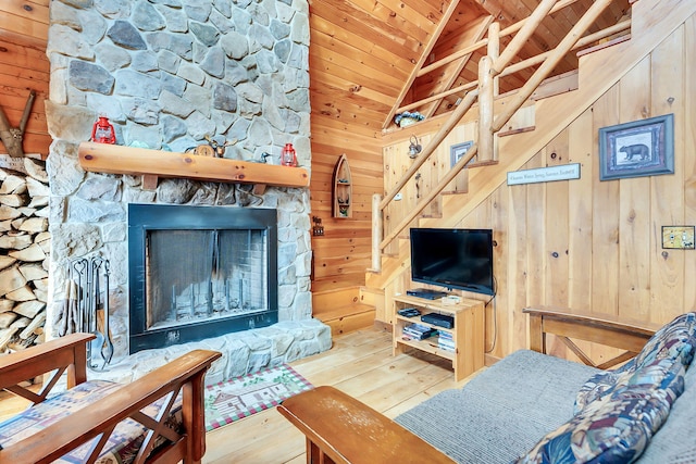 living room with lofted ceiling with beams, a stone fireplace, wooden walls, hardwood / wood-style flooring, and wood ceiling