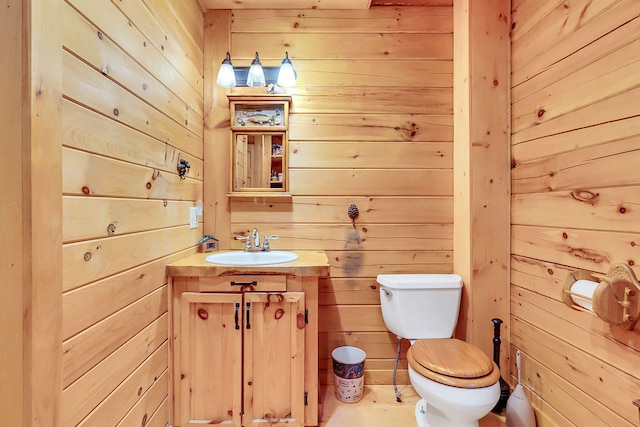 bathroom with wooden walls, vanity, and toilet