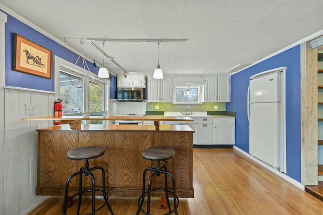 kitchen with kitchen peninsula, white cabinetry, light wood-type flooring, and white refrigerator