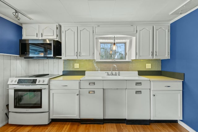 kitchen featuring wood walls, white stove, white cabinets, sink, and light hardwood / wood-style floors