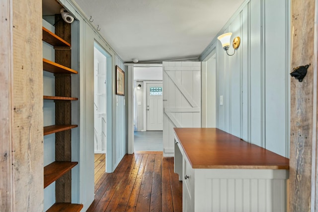 corridor featuring vaulted ceiling, a barn door, and dark hardwood / wood-style floors